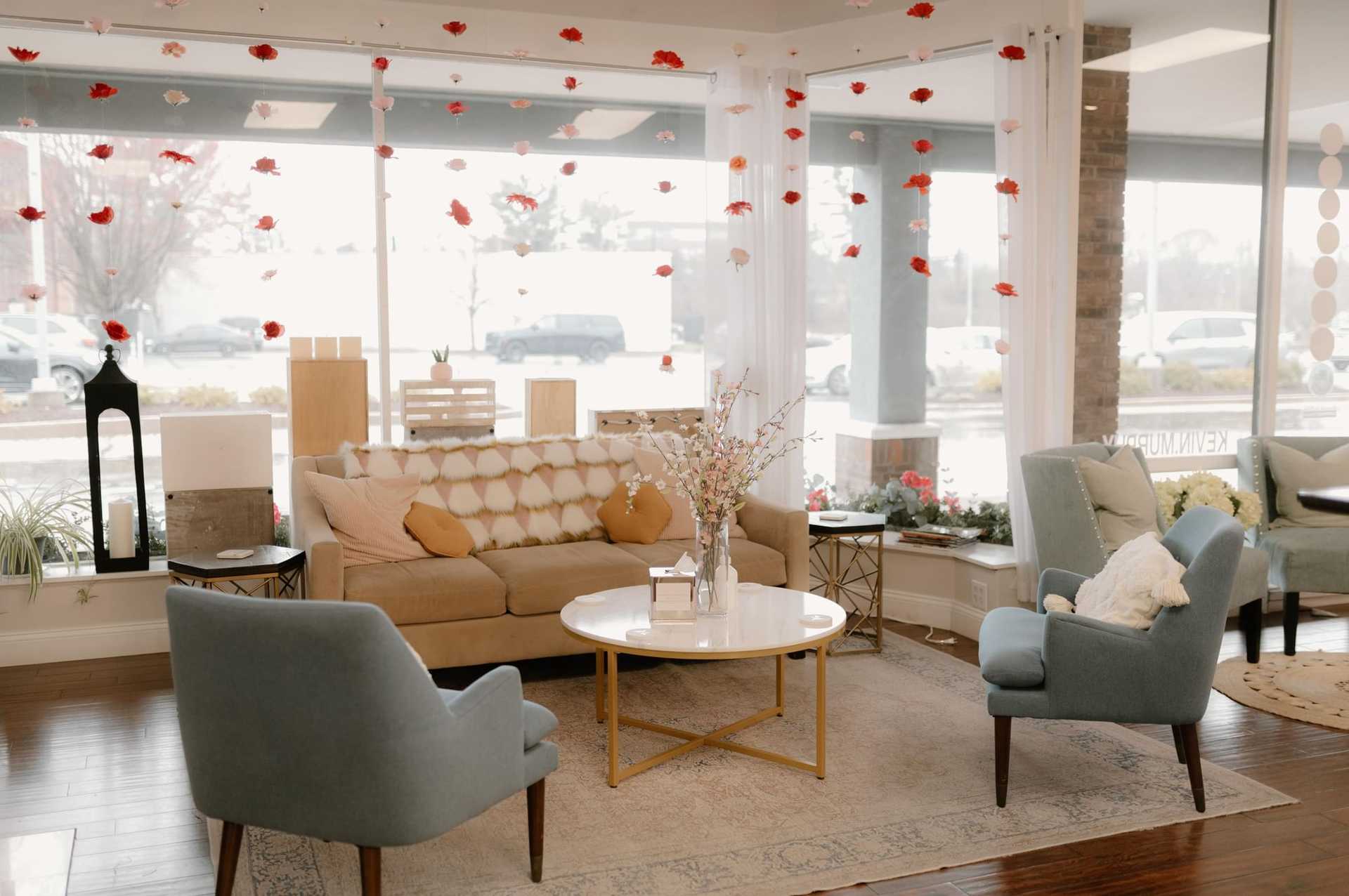 Cozy living room with plush seating, floral decorations, and large windows letting in natural light.